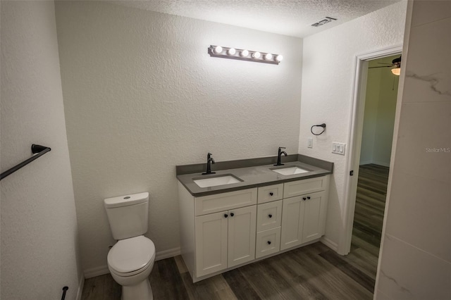 bathroom with wood-type flooring, toilet, vanity, and a textured ceiling