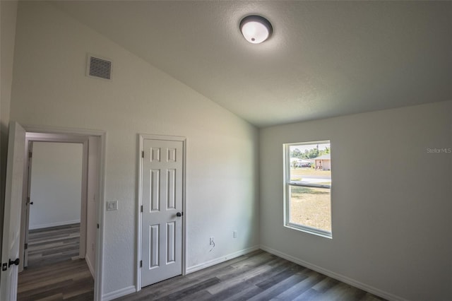 unfurnished bedroom with vaulted ceiling, dark wood-type flooring, and a textured ceiling