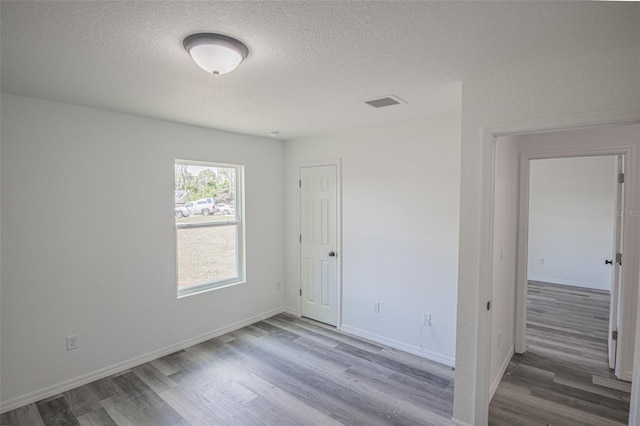 unfurnished room with hardwood / wood-style floors and a textured ceiling