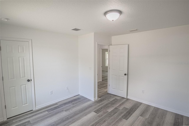 unfurnished room featuring a textured ceiling and light wood-type flooring