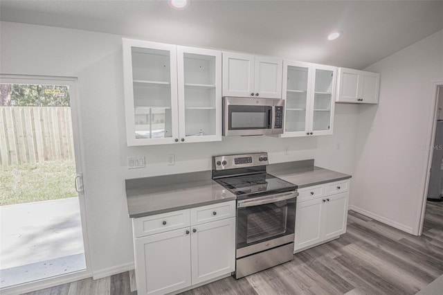 kitchen featuring stainless steel appliances, lofted ceiling, light hardwood / wood-style floors, and white cabinetry