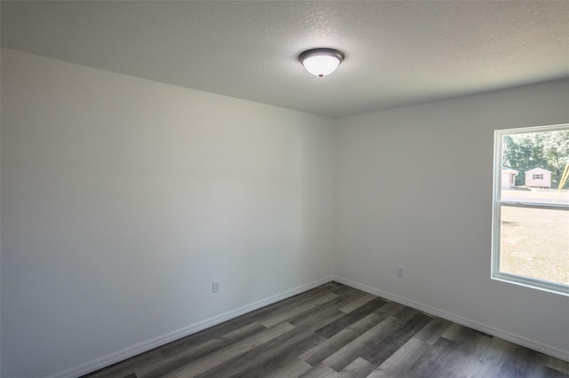 empty room featuring dark hardwood / wood-style floors, a wealth of natural light, and a textured ceiling