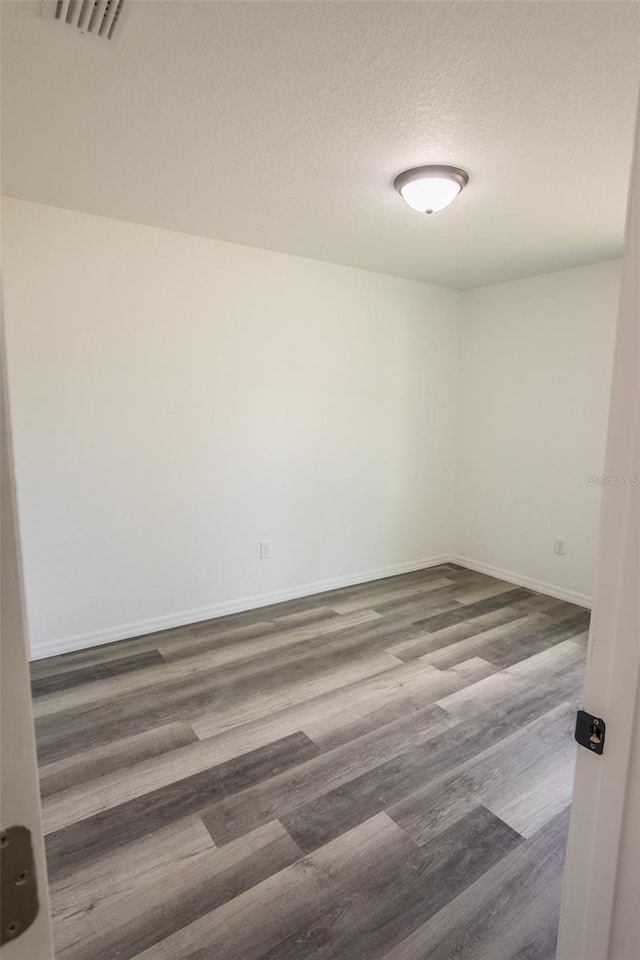 unfurnished room with a textured ceiling and dark hardwood / wood-style flooring