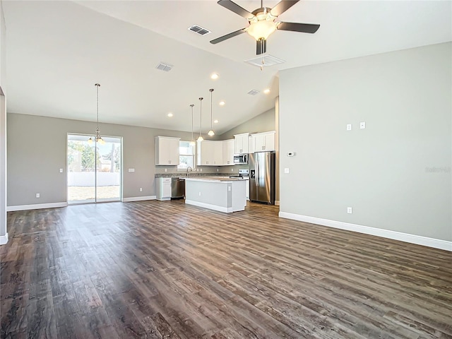 kitchen featuring pendant lighting, white cabinetry, stainless steel appliances, a center island, and vaulted ceiling