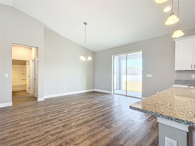 unfurnished dining area with lofted ceiling, dark hardwood / wood-style floors, and an inviting chandelier