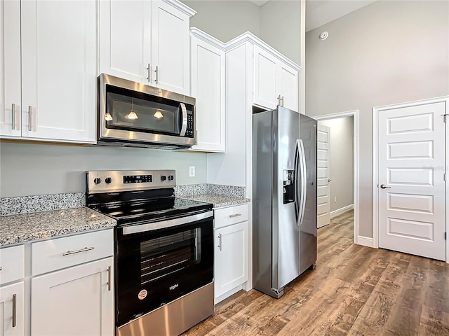 kitchen with white cabinetry, light stone counters, and appliances with stainless steel finishes