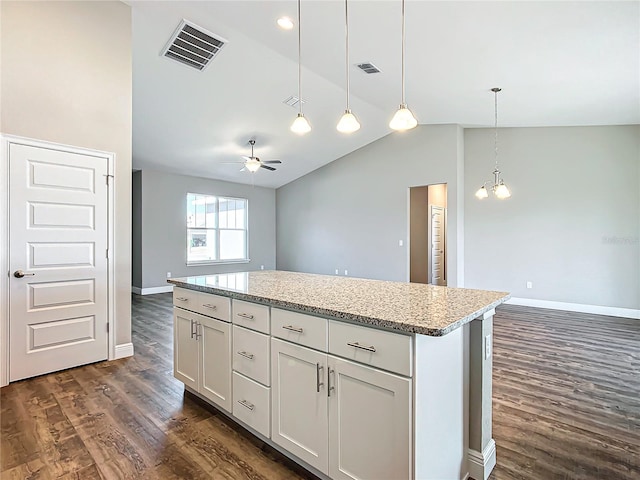 kitchen featuring white cabinetry, vaulted ceiling, hanging light fixtures, dark hardwood / wood-style flooring, and light stone countertops