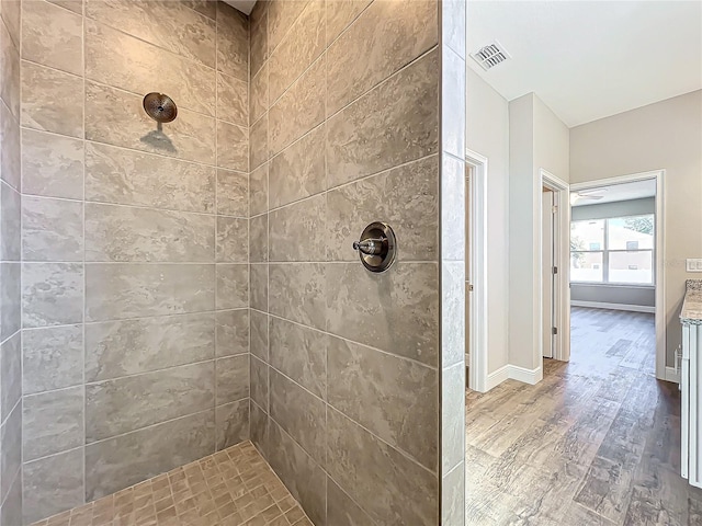 bathroom featuring wood-type flooring and a tile shower