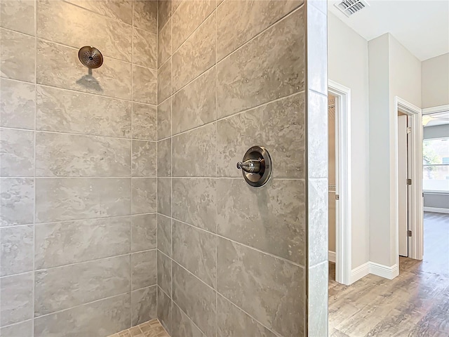 bathroom featuring hardwood / wood-style flooring and a tile shower