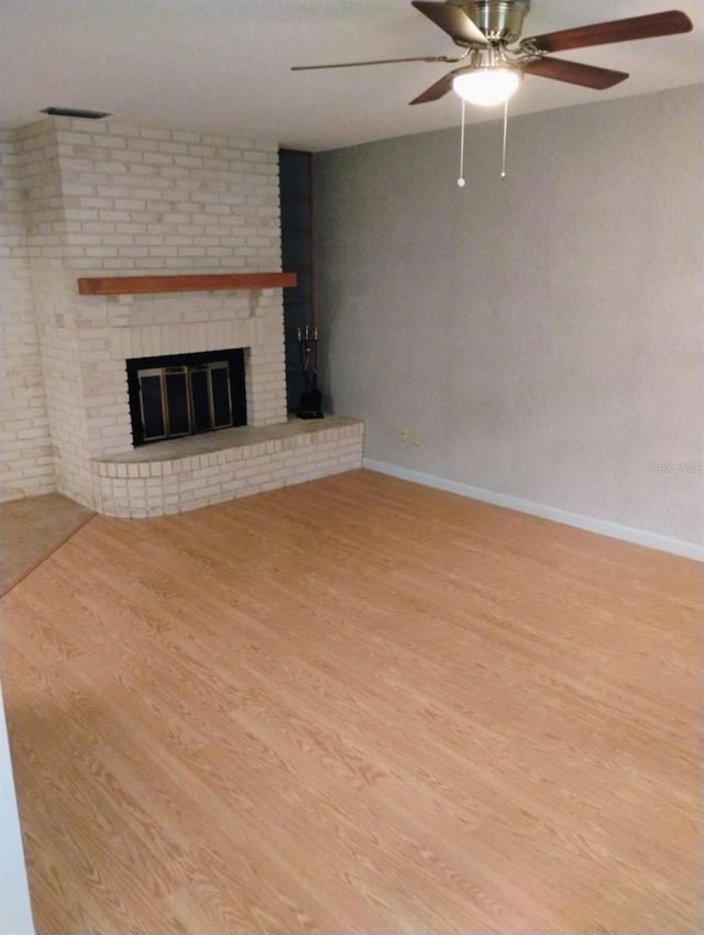 unfurnished living room featuring a brick fireplace, light hardwood / wood-style flooring, and ceiling fan