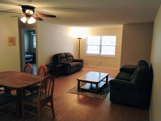 living room featuring hardwood / wood-style flooring, a textured ceiling, and ceiling fan