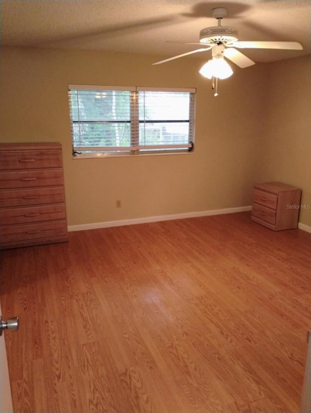 empty room with a textured ceiling, ceiling fan, and hardwood / wood-style floors