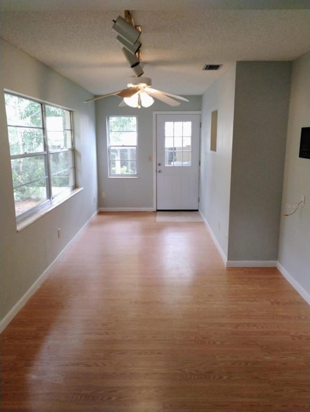 interior space featuring ceiling fan, a textured ceiling, and light hardwood / wood-style flooring