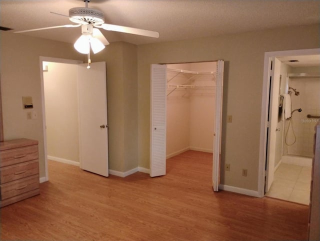 unfurnished bedroom featuring ceiling fan, light wood-type flooring, a closet, and a textured ceiling