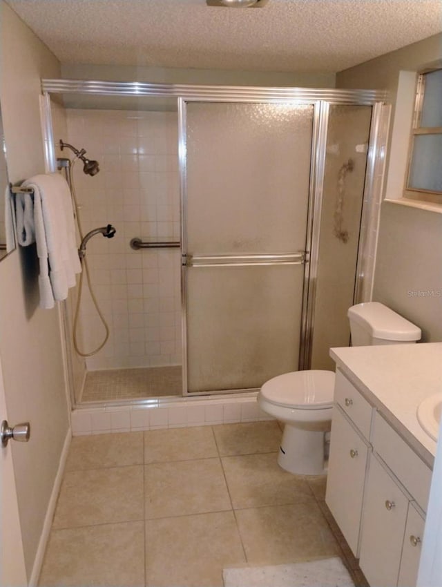 bathroom featuring toilet, vanity, a shower with door, and a textured ceiling