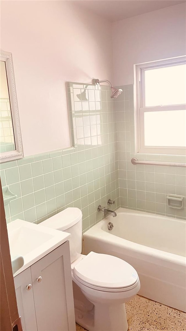 full bathroom with vanity, tiled shower / bath, tile walls, and toilet