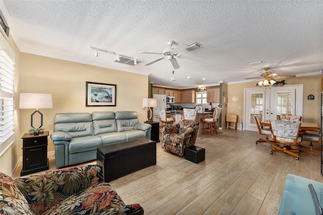 living room featuring rail lighting, french doors, crown molding, and light hardwood / wood-style flooring