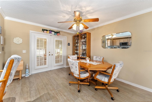 dining space with light hardwood / wood-style floors, ceiling fan, french doors, a textured ceiling, and crown molding