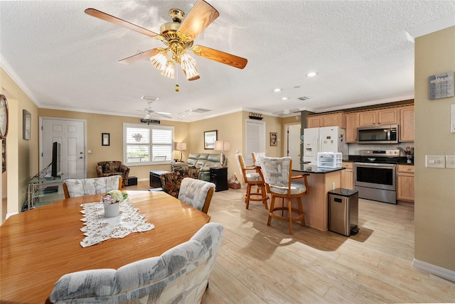 dining area with ceiling fan, crown molding, a textured ceiling, and light hardwood / wood-style flooring