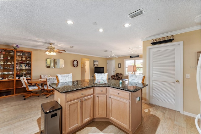 kitchen with light wood-type flooring, ornamental molding, a textured ceiling, and a center island