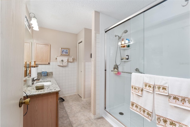 bathroom featuring tile patterned flooring, tile walls, a shower with shower door, and vanity