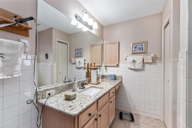 bathroom featuring tile walls, vanity, a textured ceiling, and tile patterned flooring