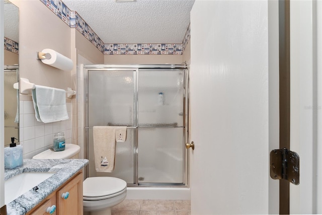 bathroom with a textured ceiling, toilet, tile walls, and an enclosed shower