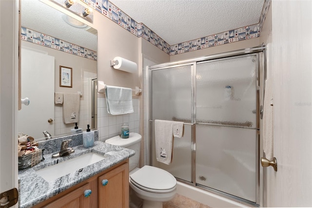 bathroom featuring an enclosed shower, vanity, tile walls, and a textured ceiling