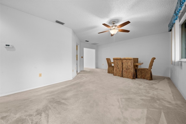 sitting room with a textured ceiling, ceiling fan, and light carpet