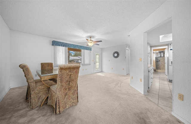 dining area featuring light carpet, ceiling fan, and a textured ceiling