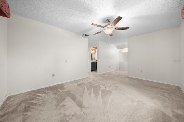 spare room with ceiling fan, light colored carpet, and a textured ceiling