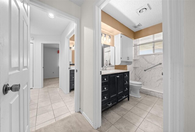 bathroom with toilet, a textured ceiling, tile patterned floors, and vanity