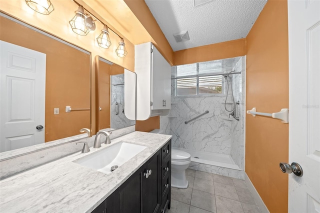 bathroom with a textured ceiling, tile patterned flooring, vanity, toilet, and tiled shower