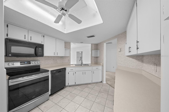 kitchen with black appliances, light tile patterned floors, sink, and white cabinetry