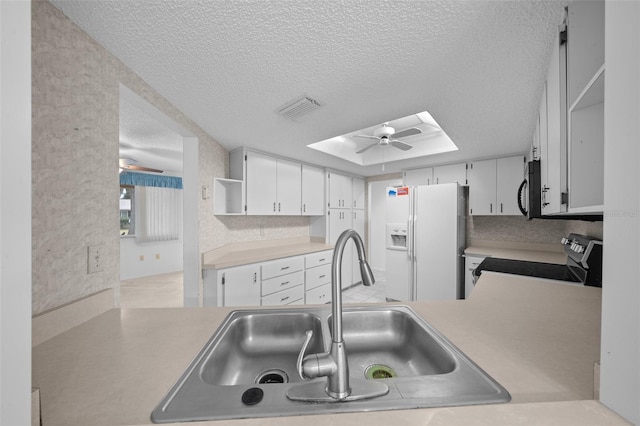 kitchen featuring white cabinets, sink, electric range, and white fridge with ice dispenser