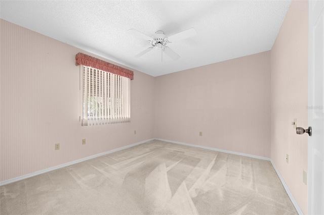 empty room featuring ceiling fan, light colored carpet, and a textured ceiling