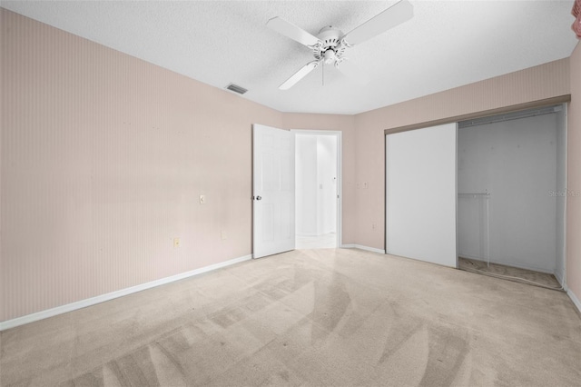 unfurnished bedroom with a textured ceiling, ceiling fan, a closet, and light colored carpet