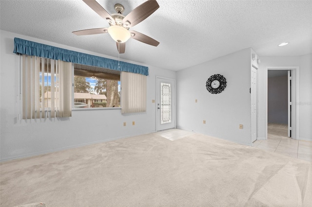 unfurnished room featuring light carpet, ceiling fan, and a textured ceiling