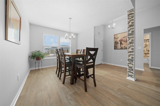 dining space with a textured ceiling, a chandelier, and light hardwood / wood-style flooring