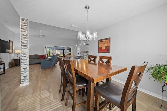 dining space with a textured ceiling, ceiling fan with notable chandelier, and light hardwood / wood-style flooring