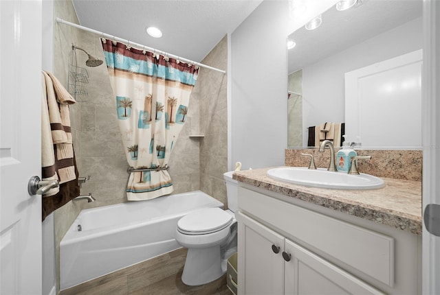 full bathroom with shower / bath combo with shower curtain, a textured ceiling, toilet, and vanity