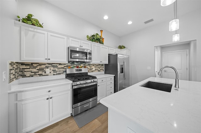 kitchen with light hardwood / wood-style floors, stainless steel appliances, decorative light fixtures, white cabinets, and sink