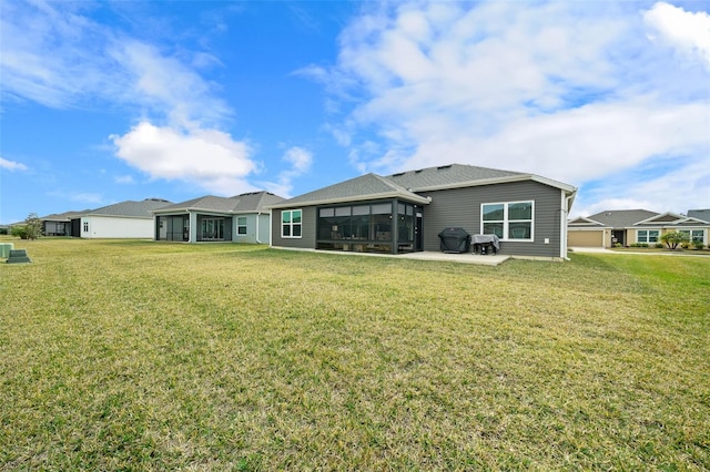 back of house featuring a sunroom, a lawn, and a patio