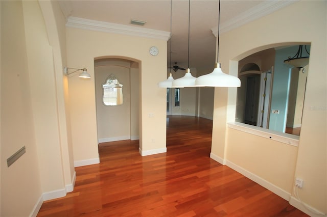 unfurnished dining area with ceiling fan, ornamental molding, and wood-type flooring