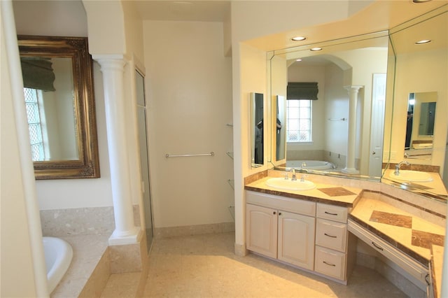 bathroom featuring ornate columns, vanity, tile patterned flooring, and a relaxing tiled tub