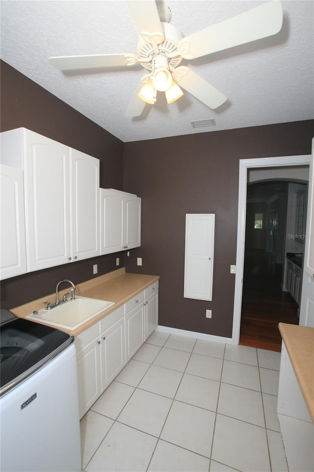 kitchen featuring white cabinetry, light tile patterned flooring, sink, and a textured ceiling