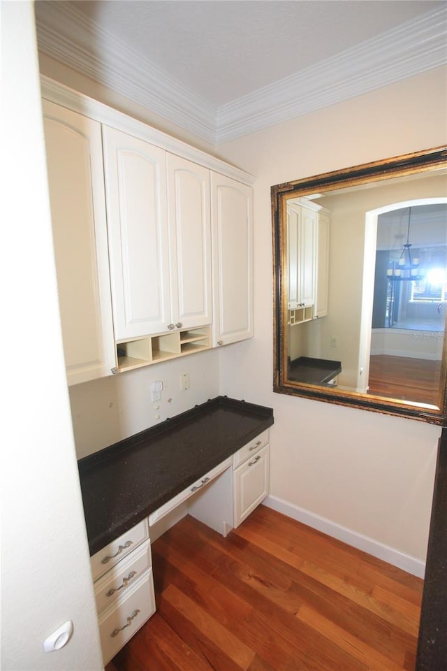 interior space featuring crown molding, built in desk, and dark hardwood / wood-style floors