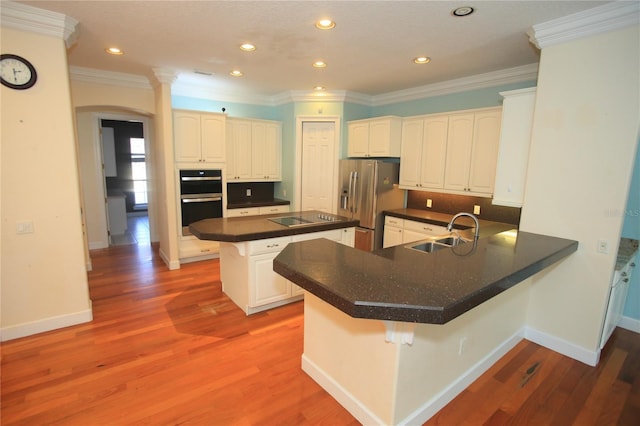 kitchen with sink, a breakfast bar, white cabinetry, stainless steel refrigerator with ice dispenser, and kitchen peninsula