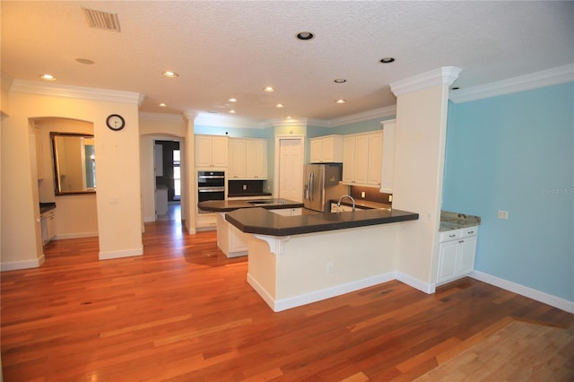 kitchen with stainless steel refrigerator with ice dispenser, hardwood / wood-style floors, white cabinets, and kitchen peninsula