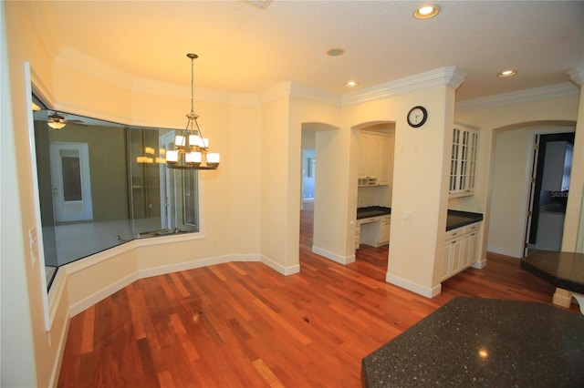 unfurnished dining area featuring hardwood / wood-style flooring, ornamental molding, and an inviting chandelier